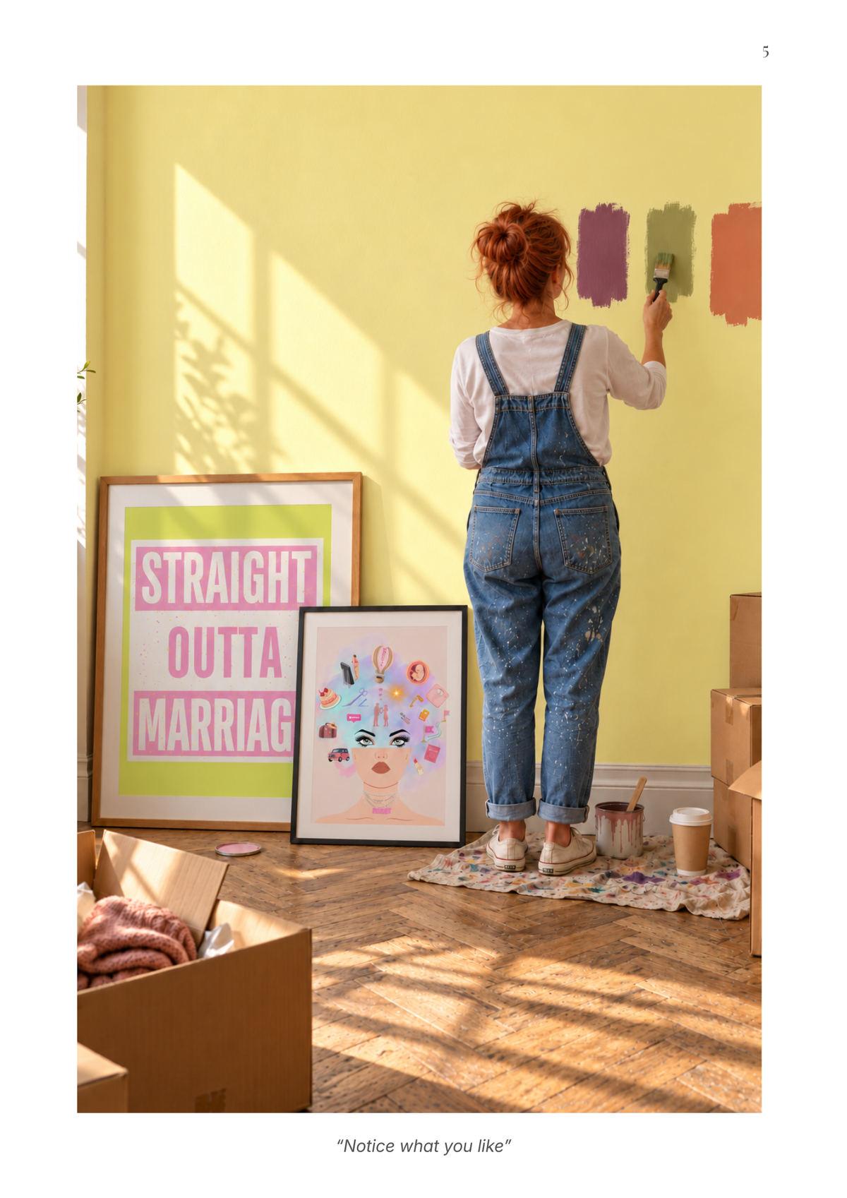 A woman in blue denim overalls stands with her back to the camera, painting a yellow wall. In the foreground, two framed art prints are leaning against the wall, one with pink and green text reading 'STRAIGHT OUTTA MARRIAGE' and the other featuring a colorful face illustration.